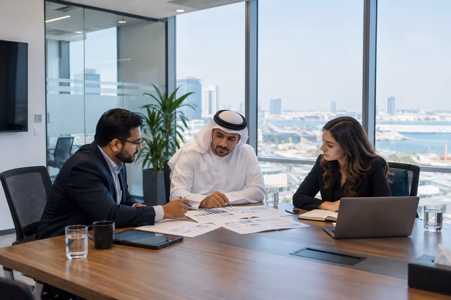 Three business professionals reviewing project plans and financial charts in an office