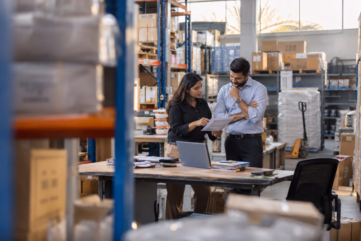 Two colleagues reviewing stock and accounting records in a UAE trading warehouse