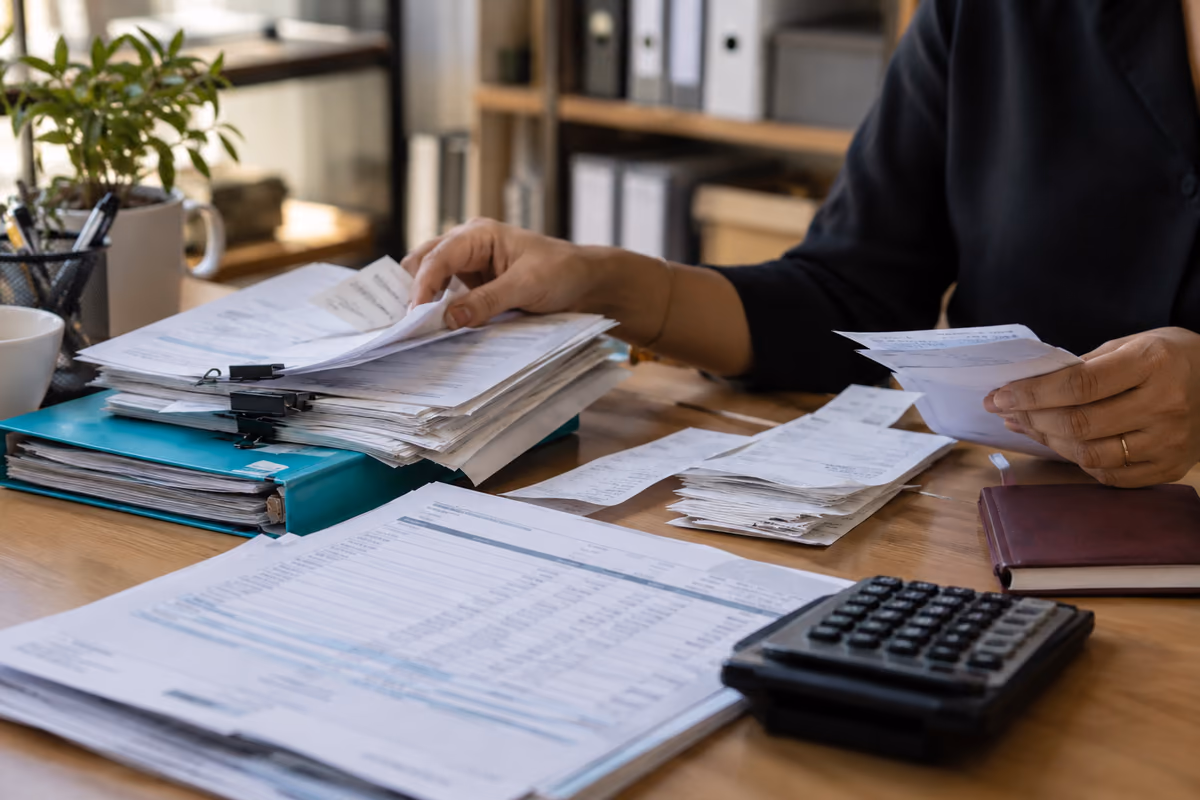 Accountant sorting invoices, receipt slips and bank records for a UAE month-end reconciliation