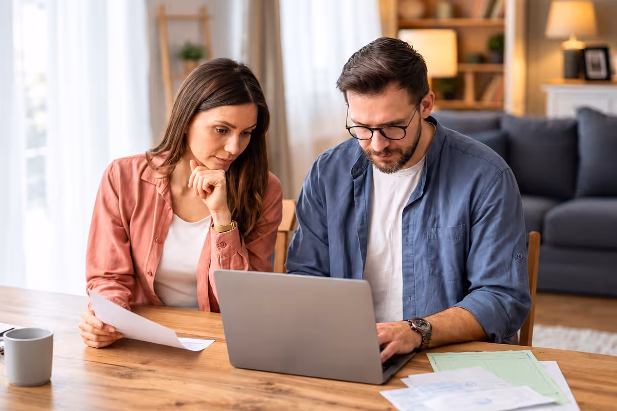Two people reviewing paperwork together beside a laptop