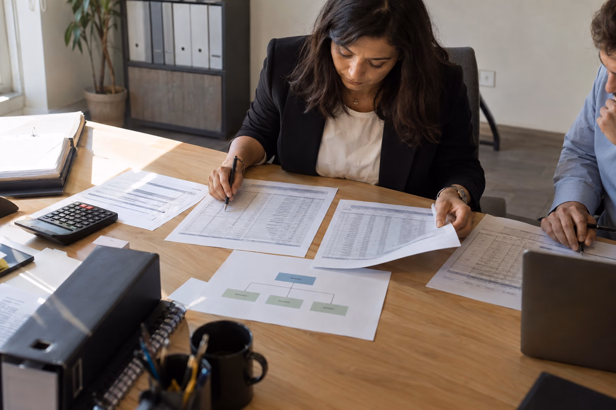 Finance team comparing separate company records and ownership papers on a desk