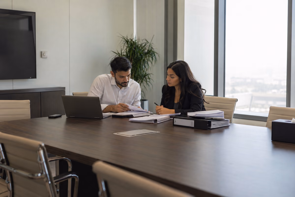 Two professionals reviewing remuneration records across a meeting table
