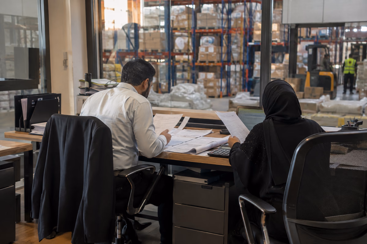 Finance professionals reviewing shipment records beside a warehouse